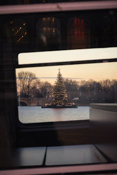 A festive Christmas tree reflecting in the Alster Lake during twilight in Hamburg, Germany.