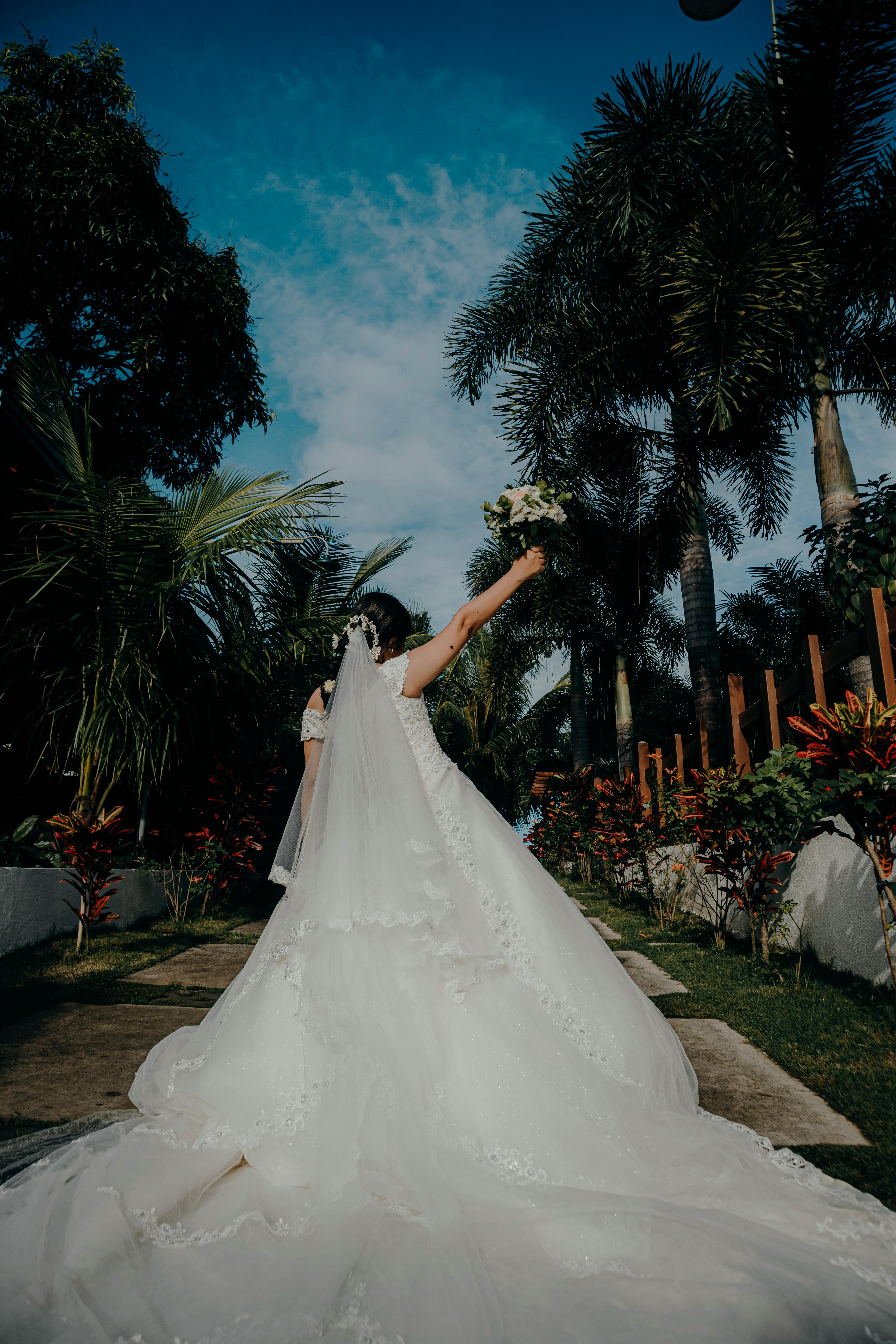 A joyful bride in a beautiful dress amidst a lush, tropical garden setting.