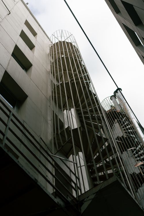Free A low-angle view of a metal outdoor spiral staircase against a modern building facade. Stock Photo