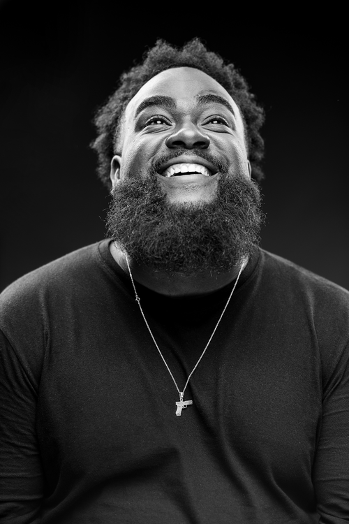 Free Monochrome portrait of a smiling man with a beard and necklace against a dark background. Stock Photo