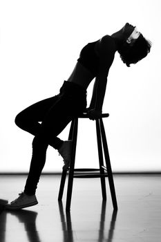 Artistic black and white silhouette of a woman leaning on a chair, conveying elegance and balance.