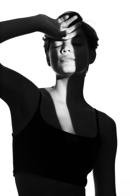 Artistic black and white portrait of a woman with shadows and closed eyes.