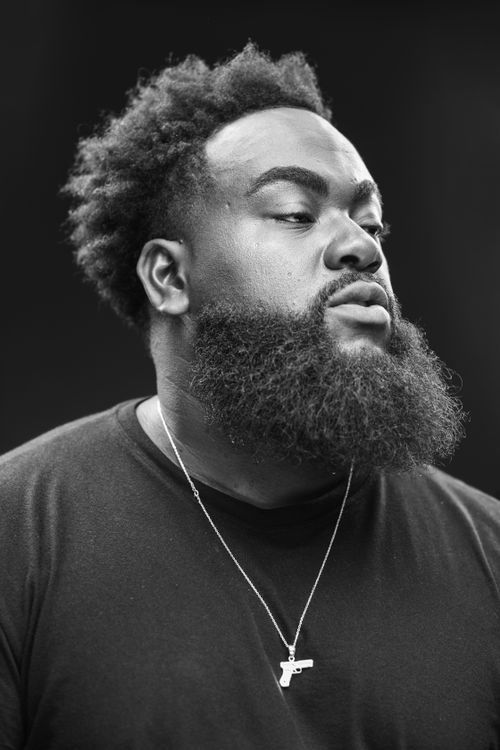 Free Black and white portrait of a bearded man wearing a necklace, deep in thought. Stock Photo