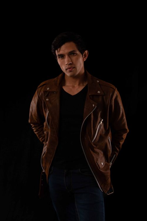 Free A fashionable portrait of a man in a brown leather jacket against a black background. Stock Photo