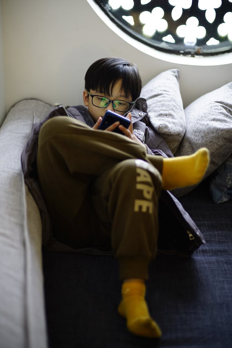 Boy Lying On Couch Using Cellphone