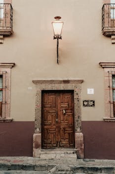 An ornate wooden door in San Miguel de Allende, accented by warm lighting and adobe walls.