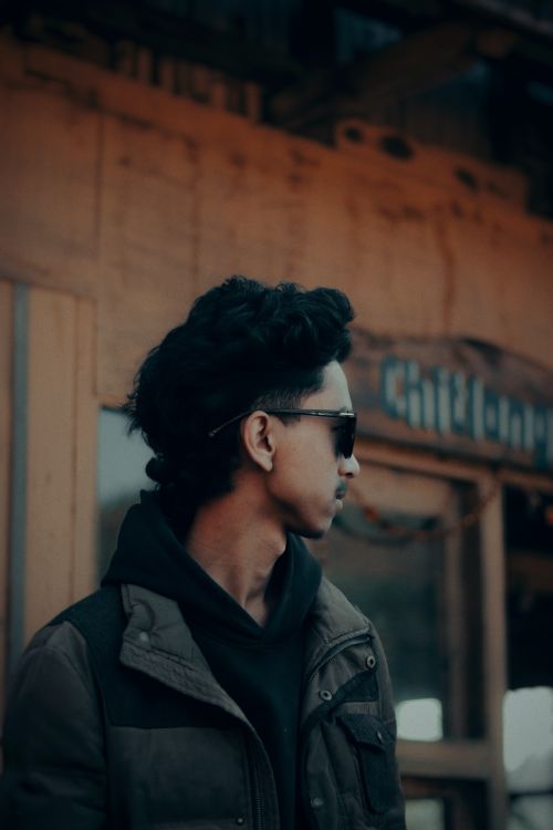 Free A fashionable young man wearing sunglasses standing outside a building. Stock Photo