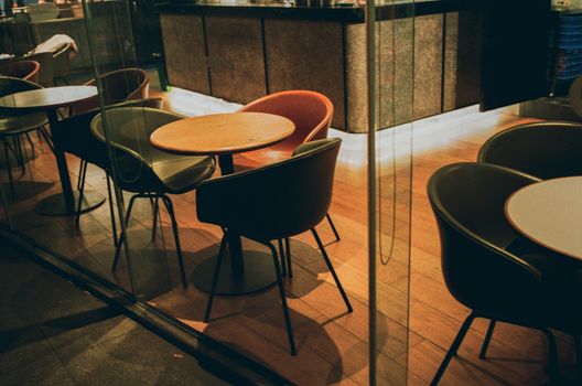 Empty café with wooden tables and chairs, modern design, warm lighting.