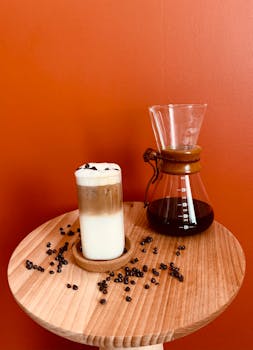 A stylish coffee arrangement featuring a latte and Chemex against a red background.