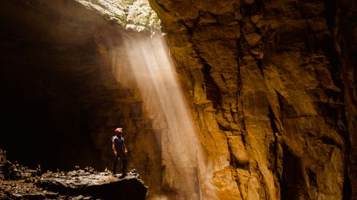 Free A lone explorer stands beneath a sunbeam in a majestic cave in Cuetzalan, Mexico, inspiring awe and adventure. Stock Photo