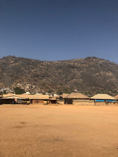 Free Traditional houses at the base of Aso Rock in Abuja, Nigeria, under a clear blue sky. Stock Photo