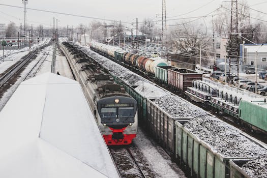 Freight and passenger trains at a snowy railway station during winter.