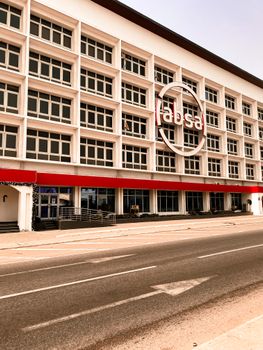 Street view of a modern office building facade with prominent logo, showcasing urban architecture.