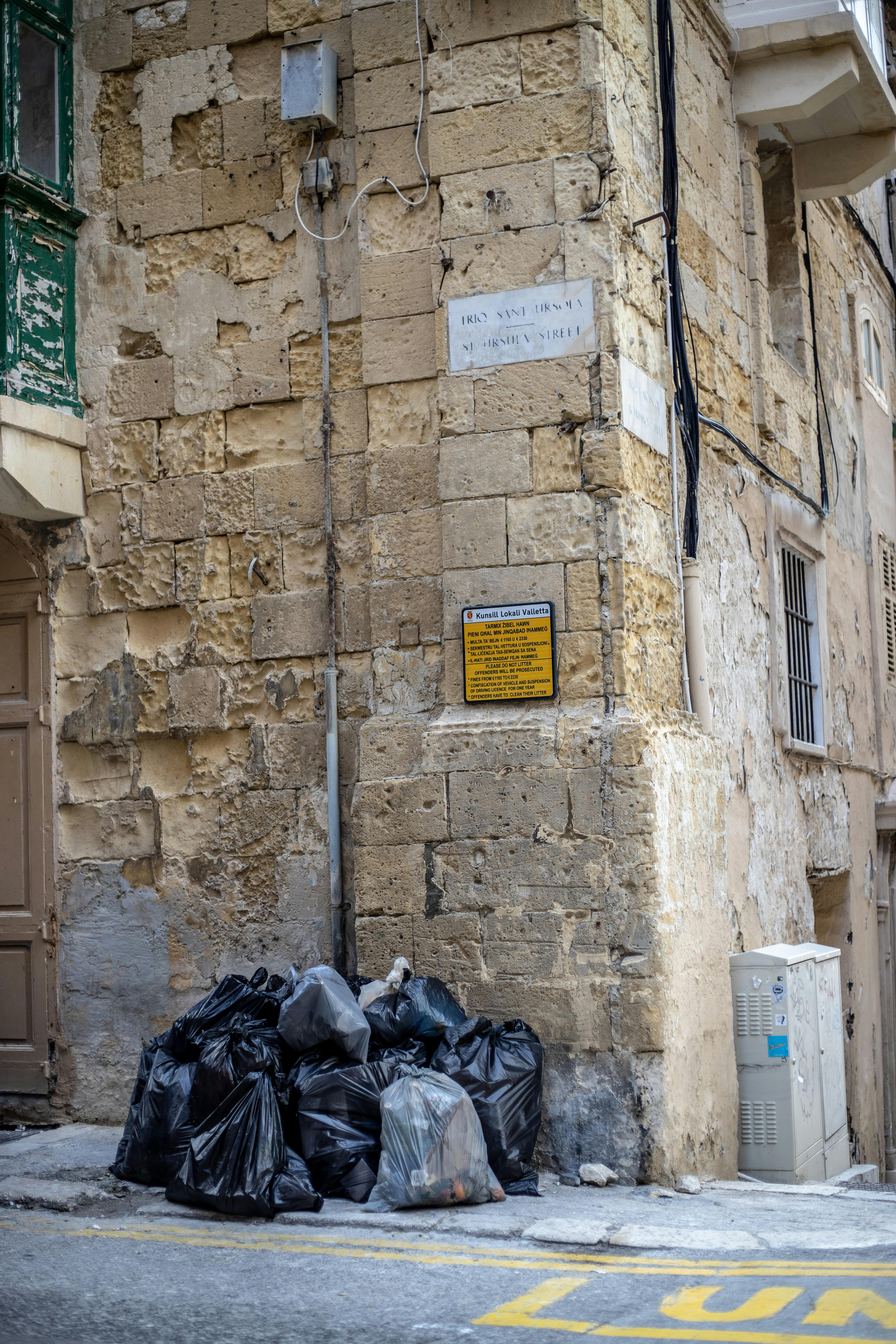 Free Pile of garbage bags on a historical urban street corner. Stock Photo