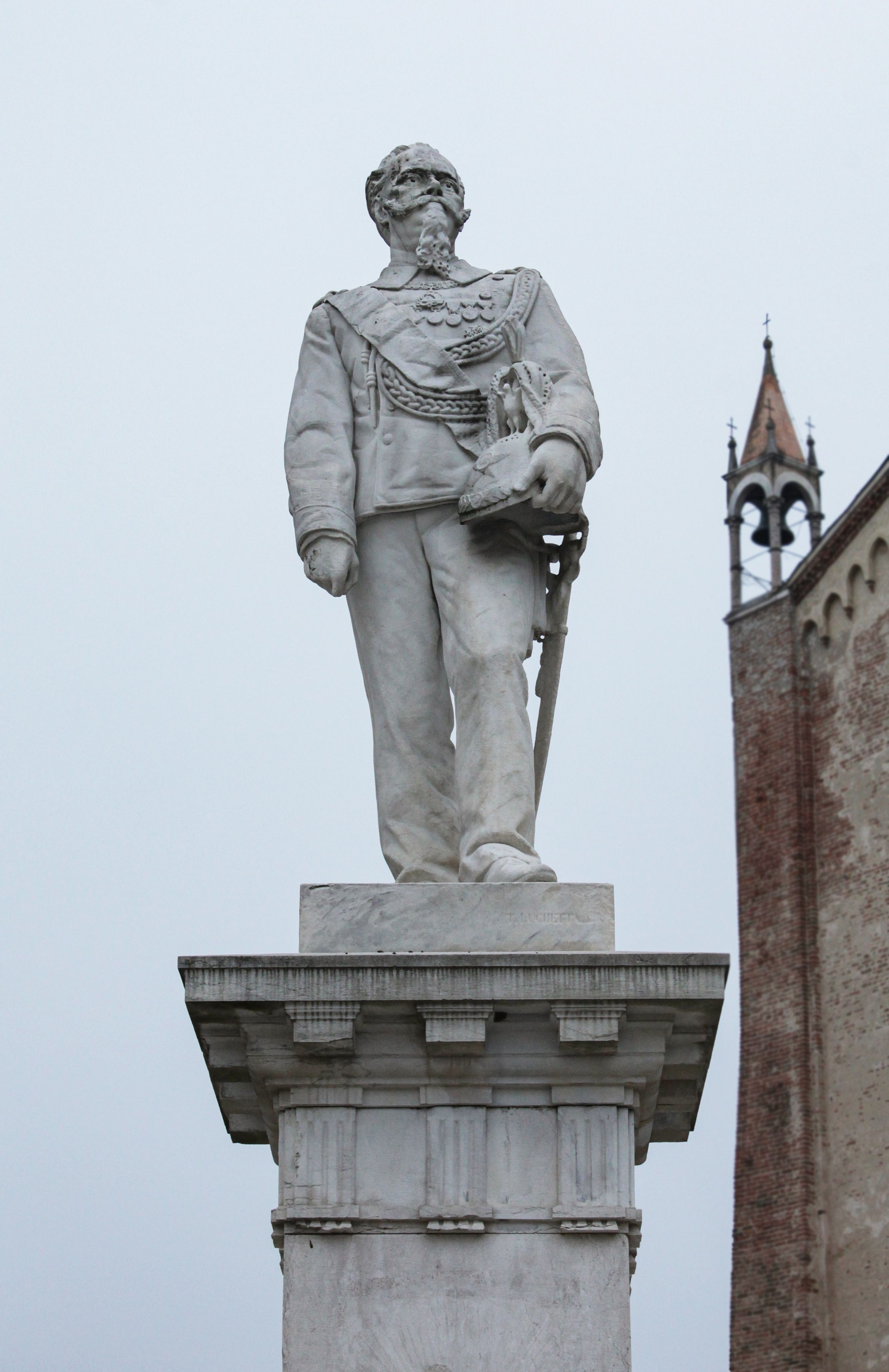 White marble statue of a historical figure on a pedestal in an urban setting.