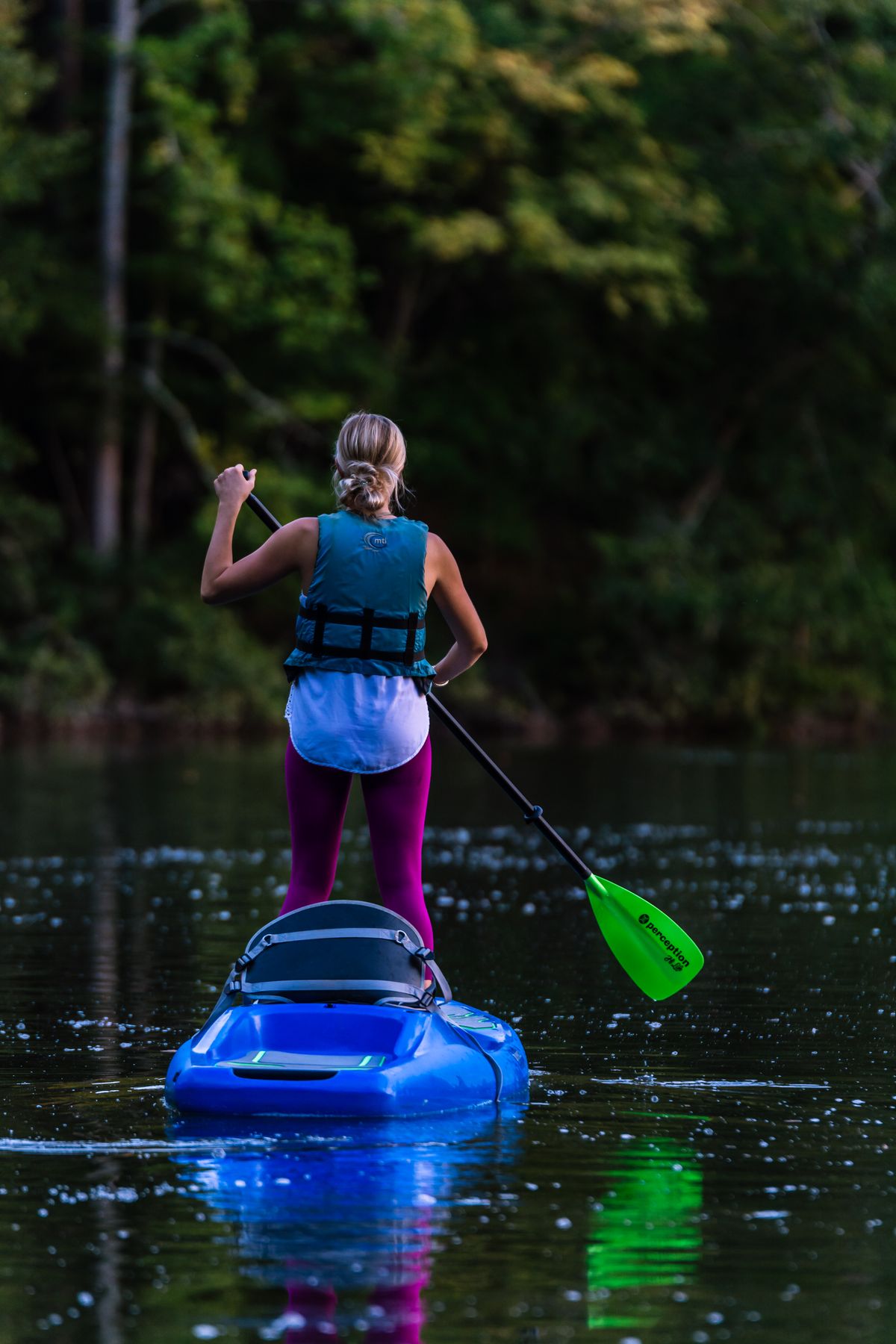 Kayaker wearing flotation gear while paddling on calm open water