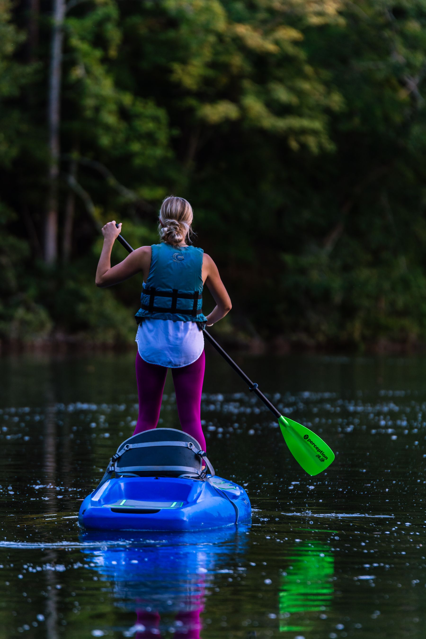 Woman kayaking on calm water while wearing a life vest