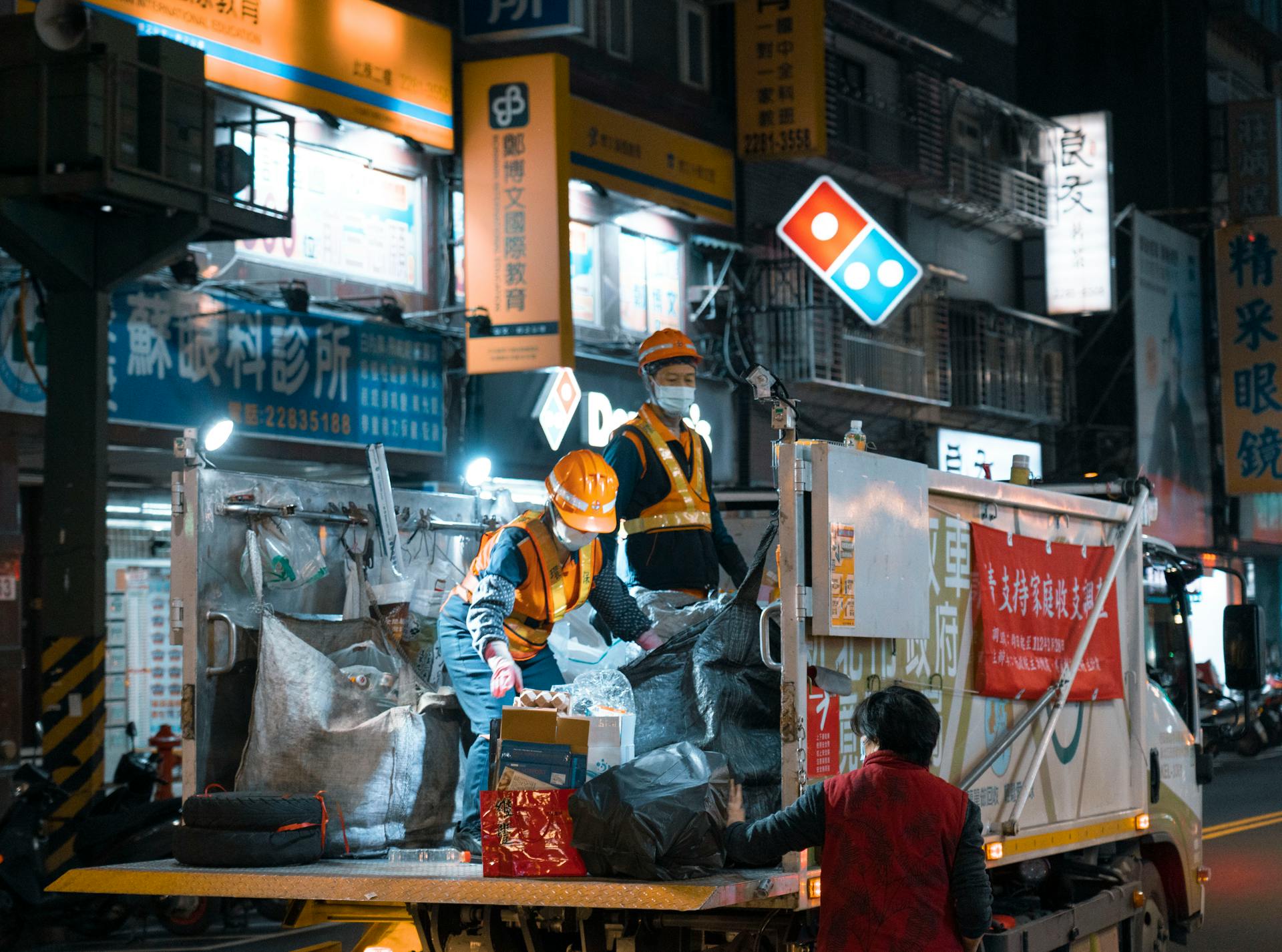 Men Collecting Garbage in City at Night
