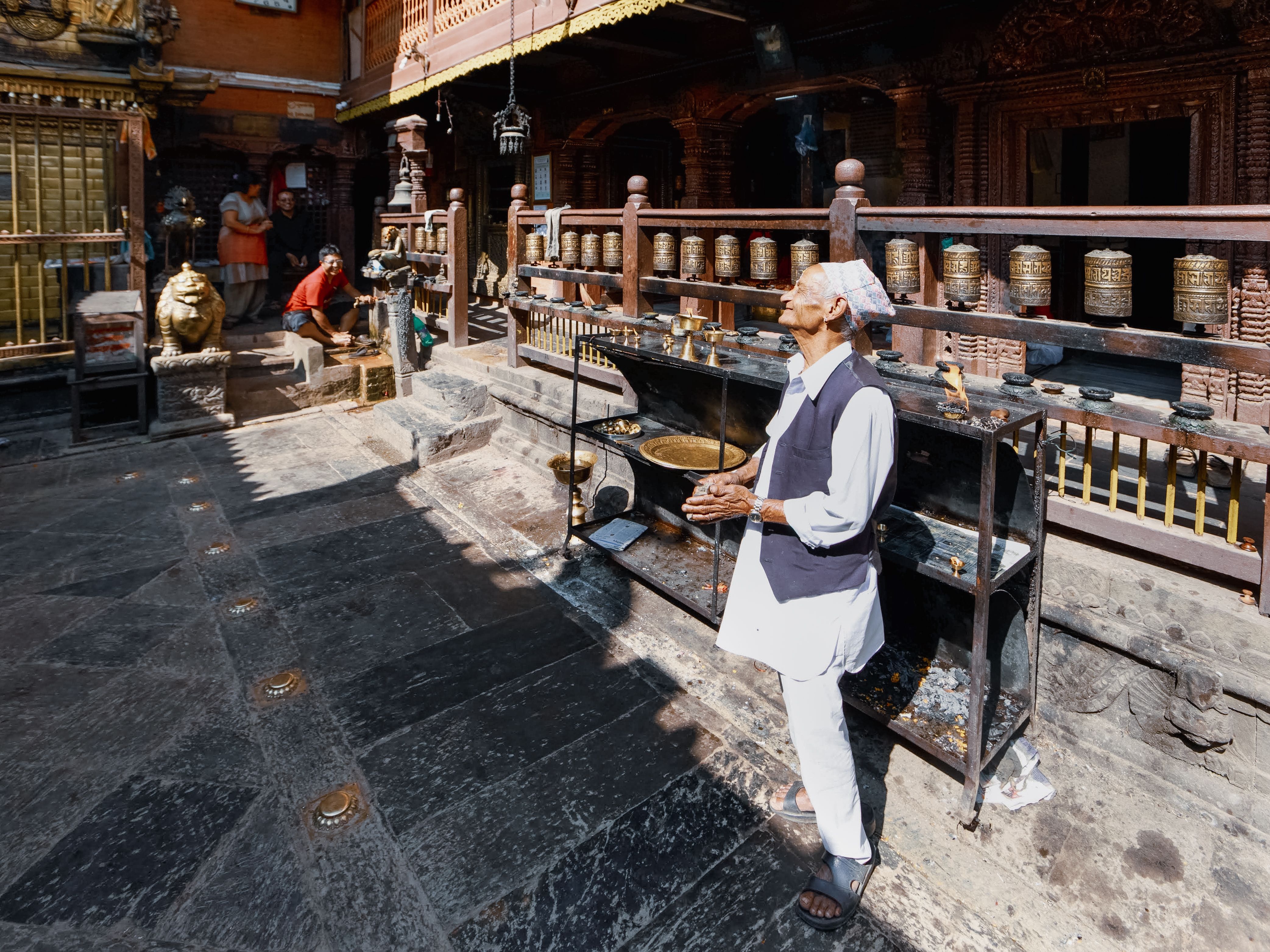 A serene temple courtyard with elderly man engaged in ritual, showcasing cultural spirituality.