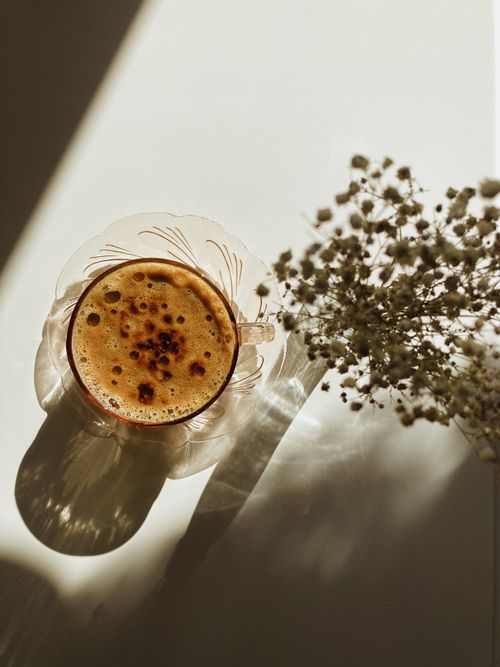 Free Elegant still life of a coffee cup with floral decor in shadowed sunlight. Stock Photo