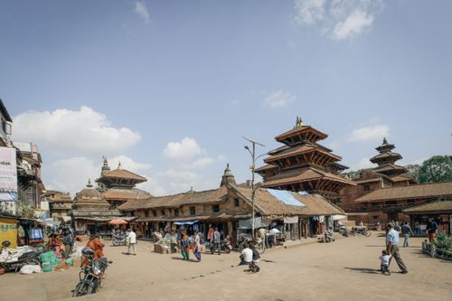 Free Vibrant marketplace with traditional pagoda-style buildings and local pedestrians at Durbar Square. Stock Photo