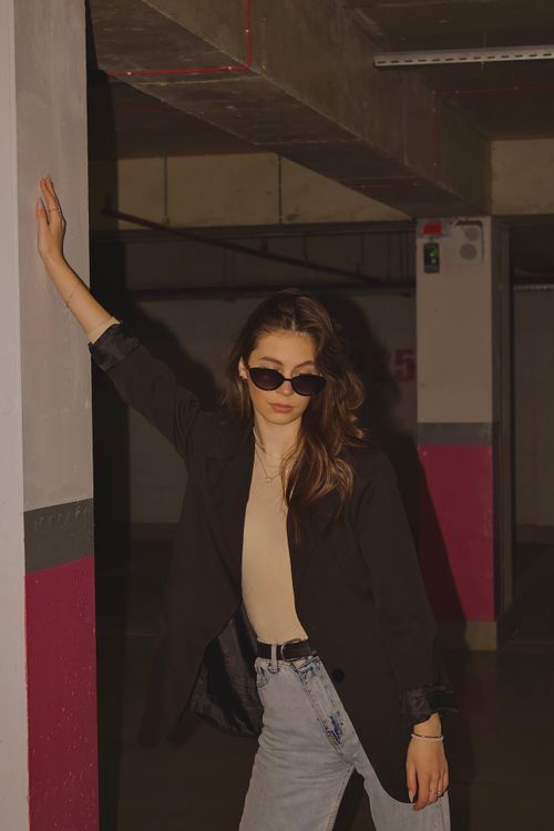Free Stylish woman in black blazer and sunglasses poses in an urban parking garage. Stock Photo