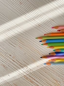 A vibrant arrangement of colored pencils on a textured wooden surface. Perfect for creativity and art themes.
