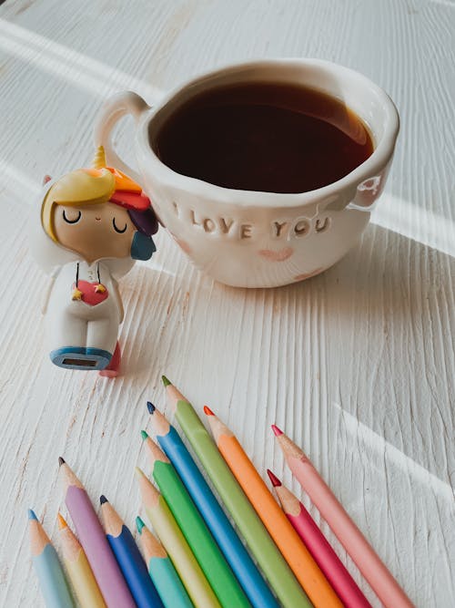 Free Tea in Cup near Figure and Colorful pencils on Table Stock Photo