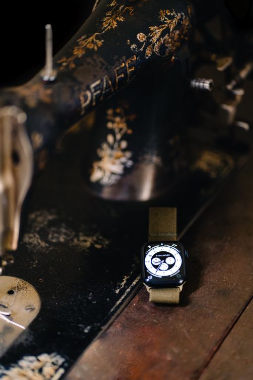 Free A vintage sewing machine beside a modern smart watch, highlighting contrast between old and new technology. Stock Photo