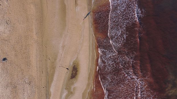 A captivating drone shot of a sandy beach meeting the ocean waves in Valencia, Spain.