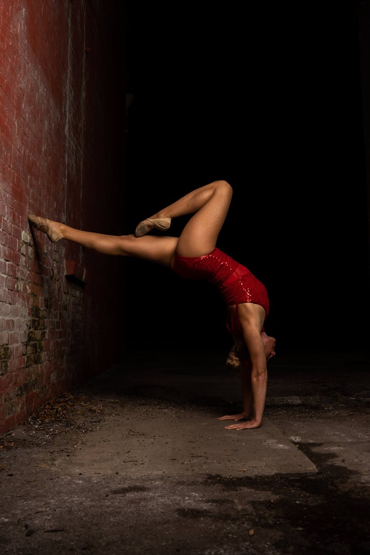 A Gymnast In Upside Down Position Leaning On Brick Wall