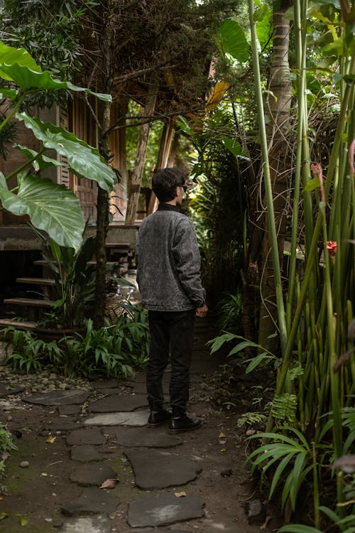 Man Standing in Front of a House Looking Into the Surrounding Jungle