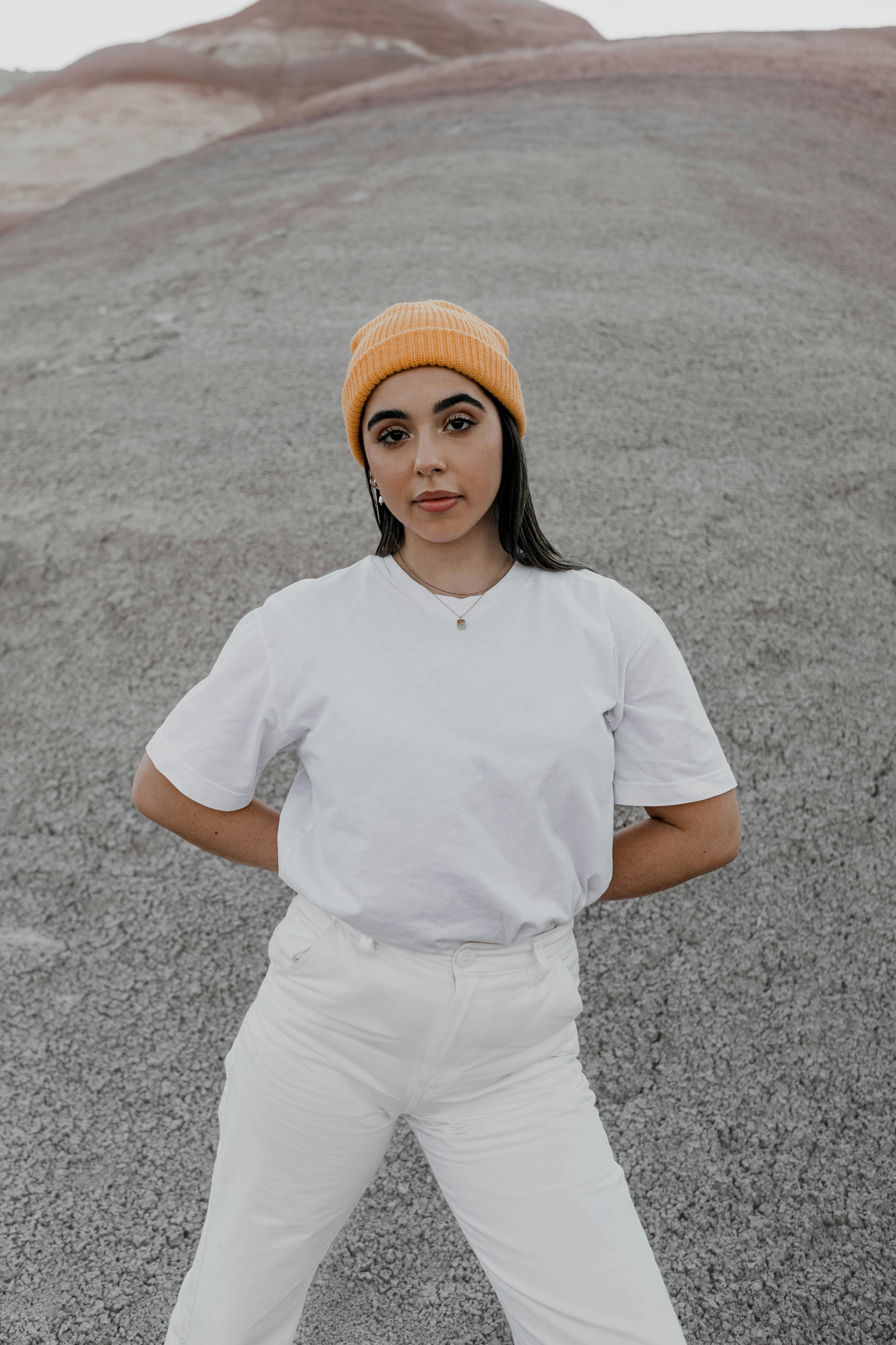 Stylish woman in white outfit and beanie posing confidently outdoors.