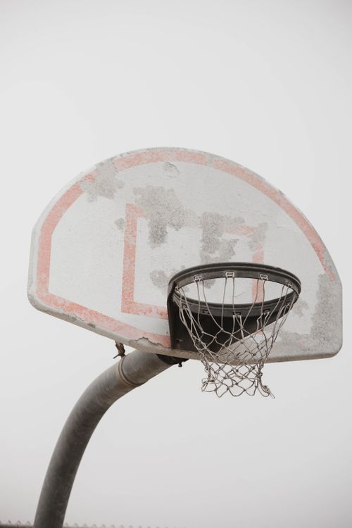 Free An old basketball hoop showing wear under an overcast sky, symbolizing endurance and outdoor activity. Stock Photo