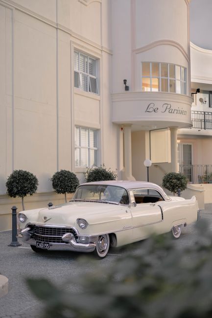 A classic white car parked outside the luxury hotel Le Parisien, capturing vintage elegance.