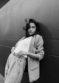Black and white portrait of a woman posing confidently against a modern wall.