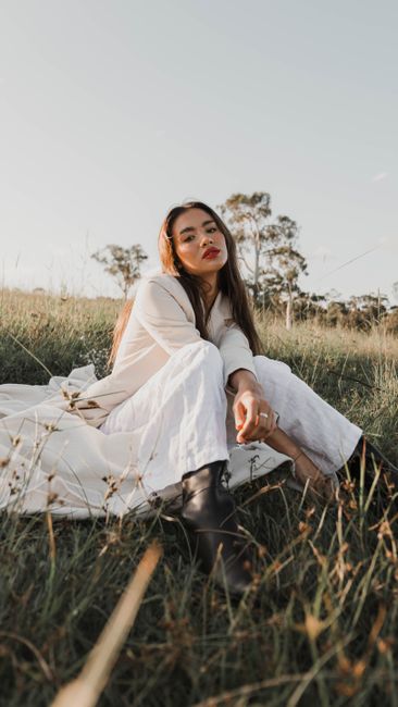 A fashionable woman posing in a meadow, showcasing casual elegance in nature.