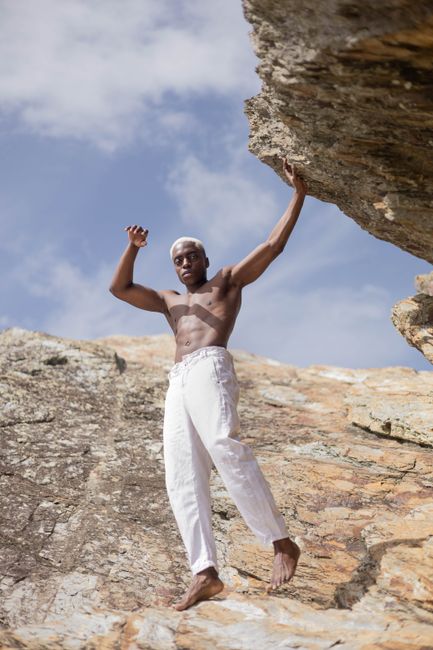 Barefoot muscled man standing on rocky terrain, showcasing strength and balance in a natural setting.