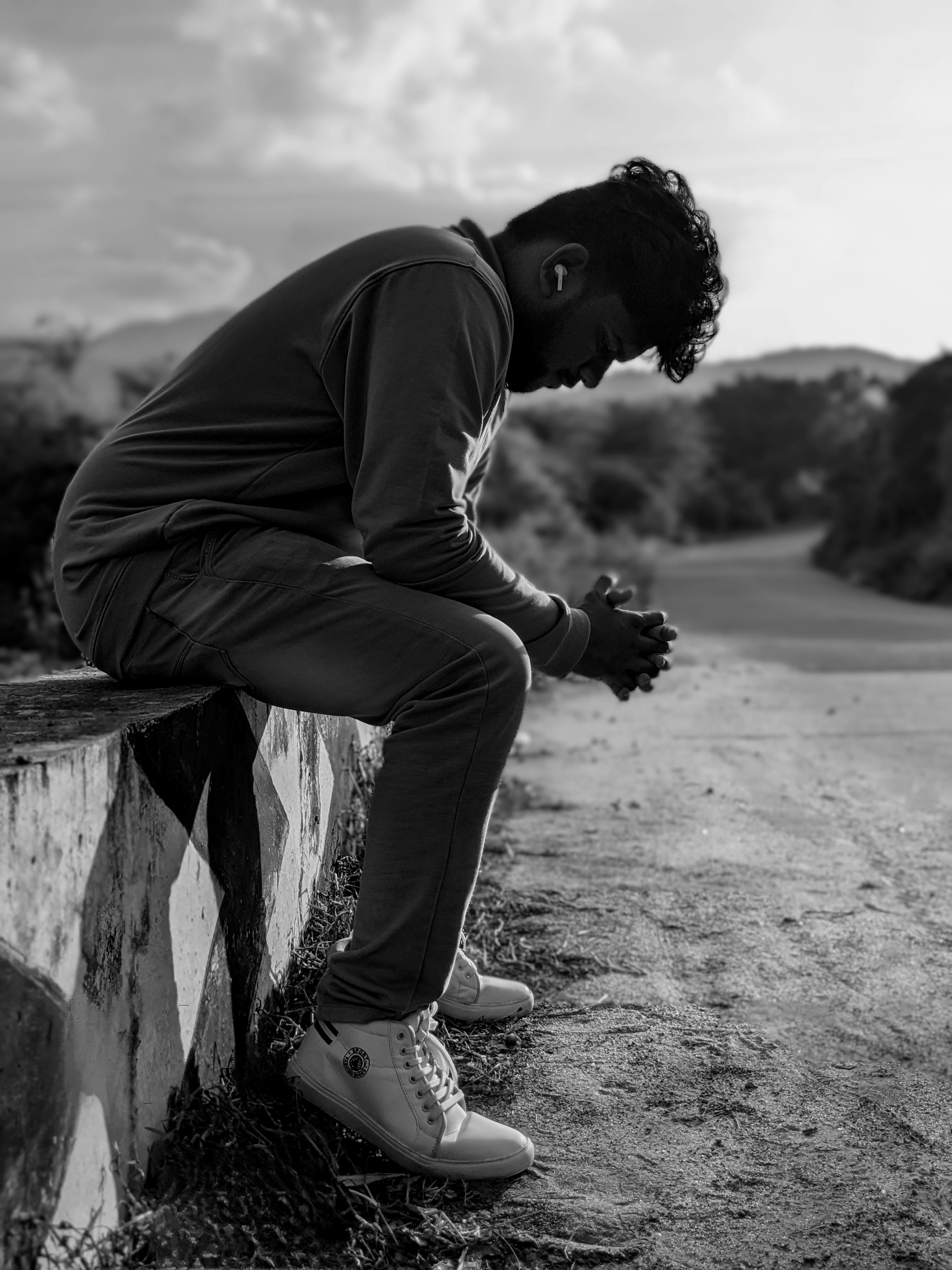 Man Sitting on a Low Wall by a Dirt Road · Free Stock Photo