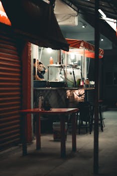 Nighttime street food stall with a vendor waiting for customers, lit by ambient street lighting.