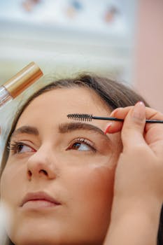 Makeup artist applying eyebrow gel to a young woman's brows with precision.