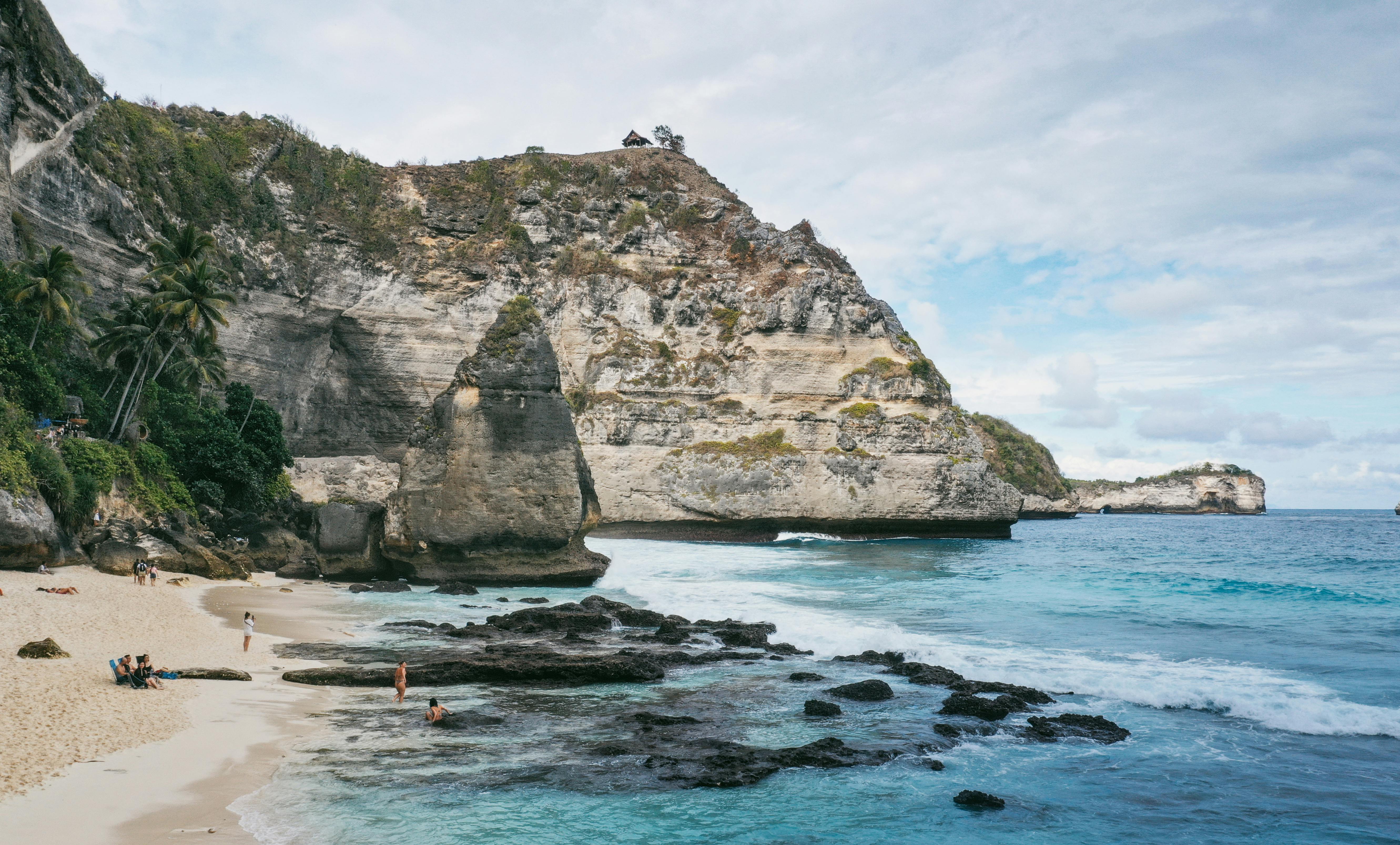 Gray rocky mountain beside blue sea during daytime photo – Free