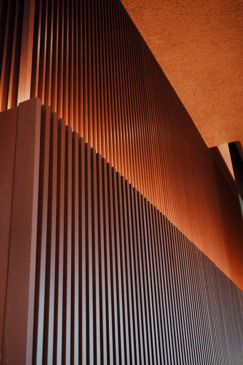 Free A close-up view of a modern vertical facade showcasing geometric patterns with warm lighting. Stock Photo