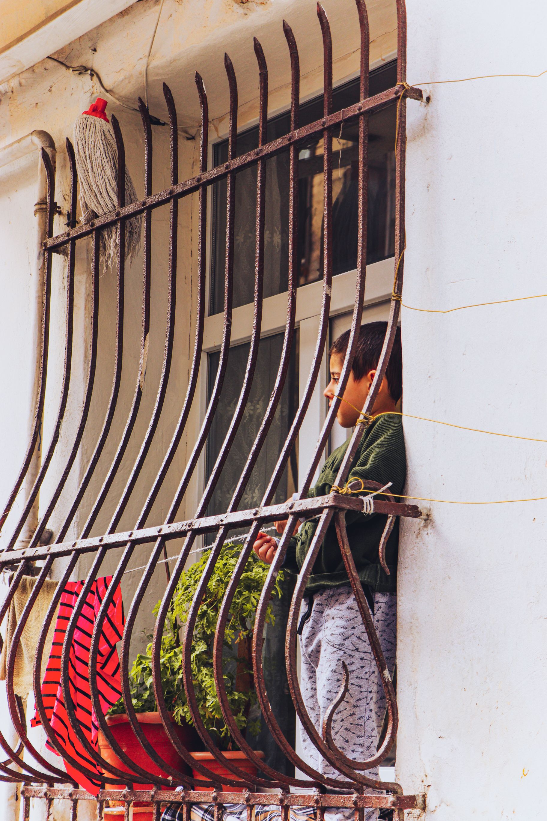 Boy Standing behind Bars in Apartment Window · Free Stock Photo