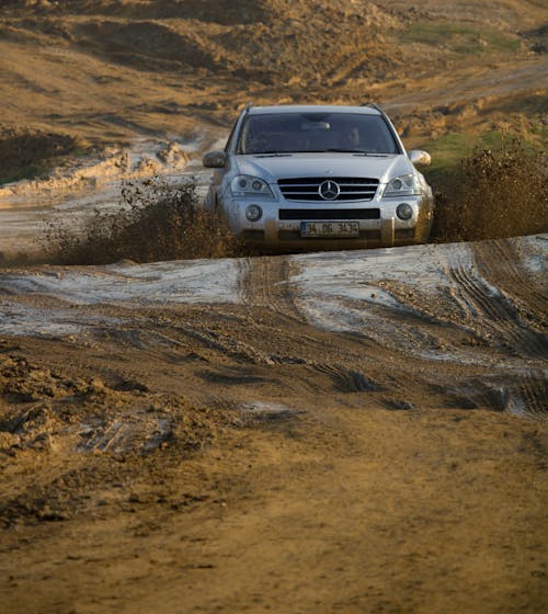 A Mercedes Driving on a Dirt Road and Splashing Mud