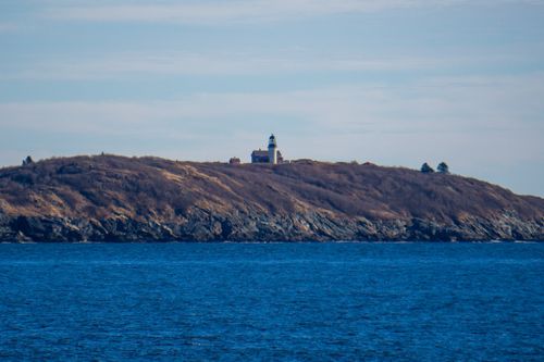 Free Peaceful view of a lighthouse perched on a rocky island overlooking the sea. Stock Photo