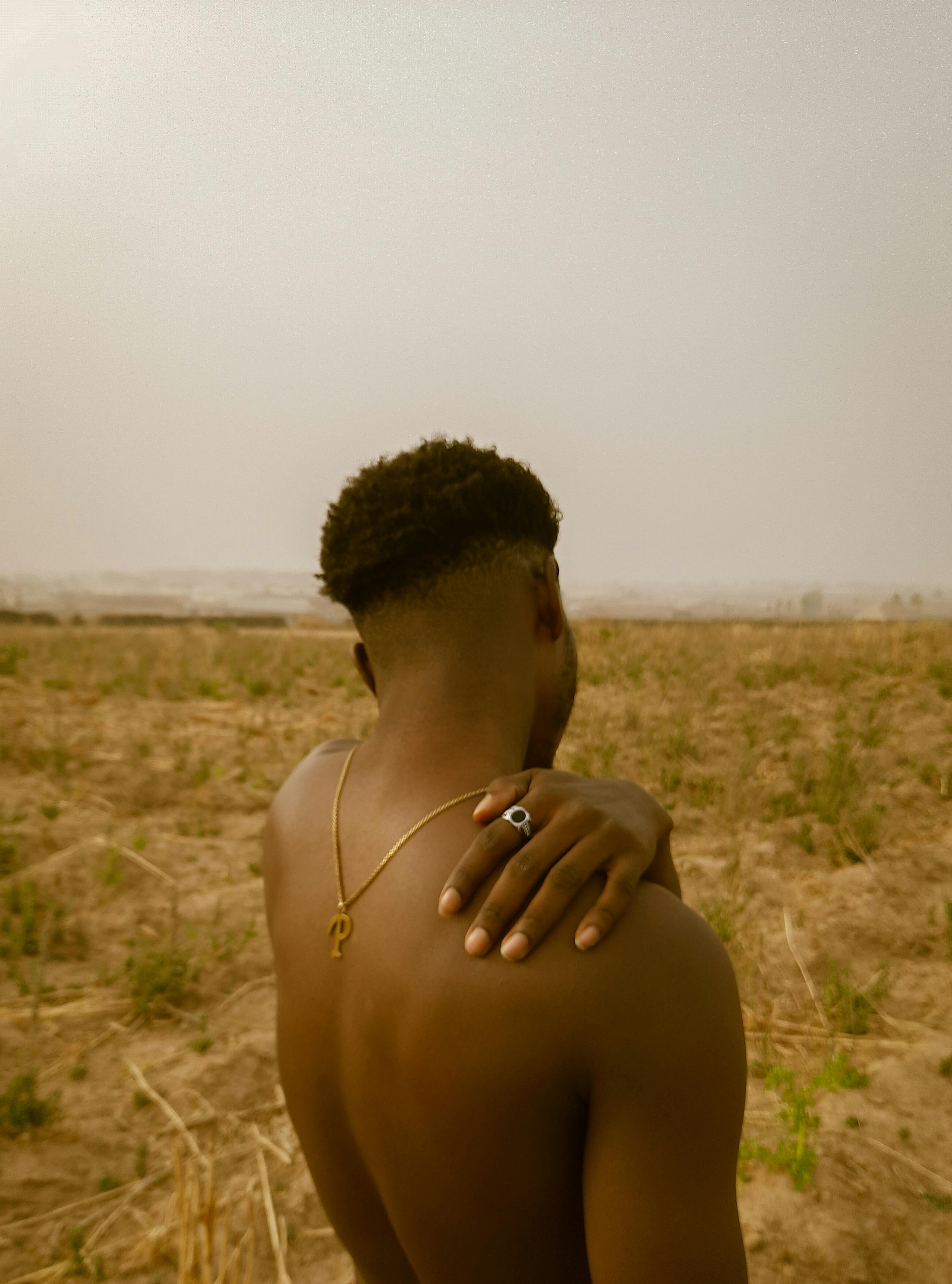 Back View of a Shirtless Man Standing on a Meadow · Free Stock Photo