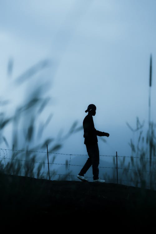 Silhouette of a Man Walking on a Hill at Dusk 