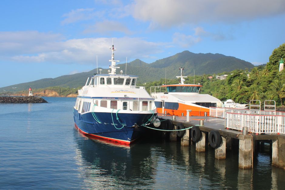 Ferry boats at a scenic tropical harbor with mountains in the background.