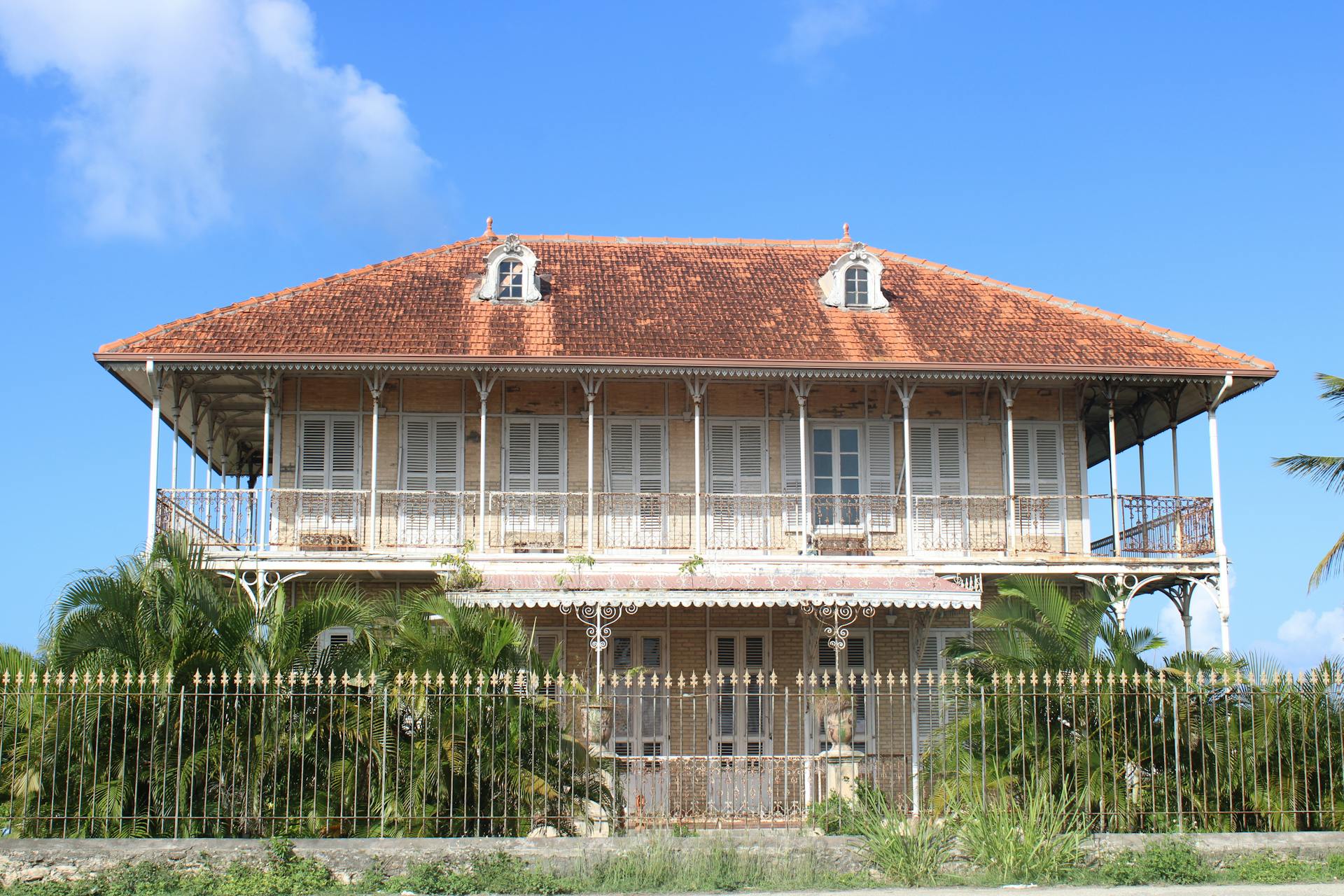 Historic French colonial house with brown roof in Guadeloupe captured on a sunny day.